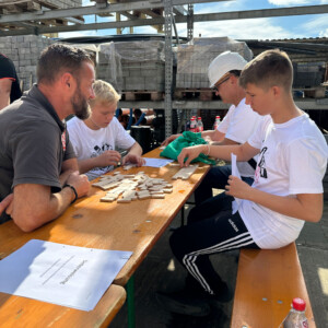 Die Schüler Kenny Swaczyna (r.) und Jordan Reß sowie Dirk Neumann, Hauptgeschäftsführer der Handwerkskammer Halle, üben Verlegmuster mit Bausteinen.